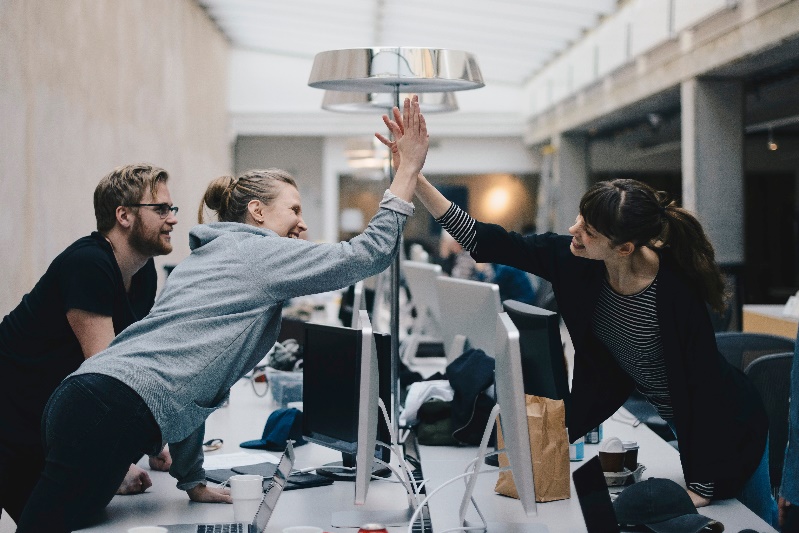 A group of young office workers give each other a hi-five after successfully completing a project.