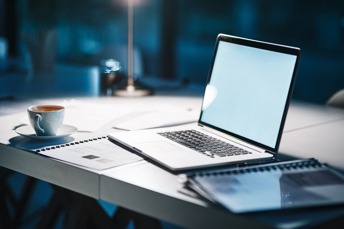 An open laptop computer next to a cup of coffee.